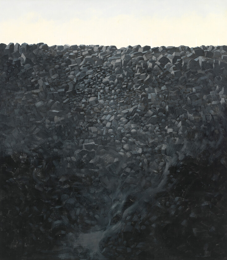 Dense dark pile of angular rocks forming a steep slope under a pale sky.