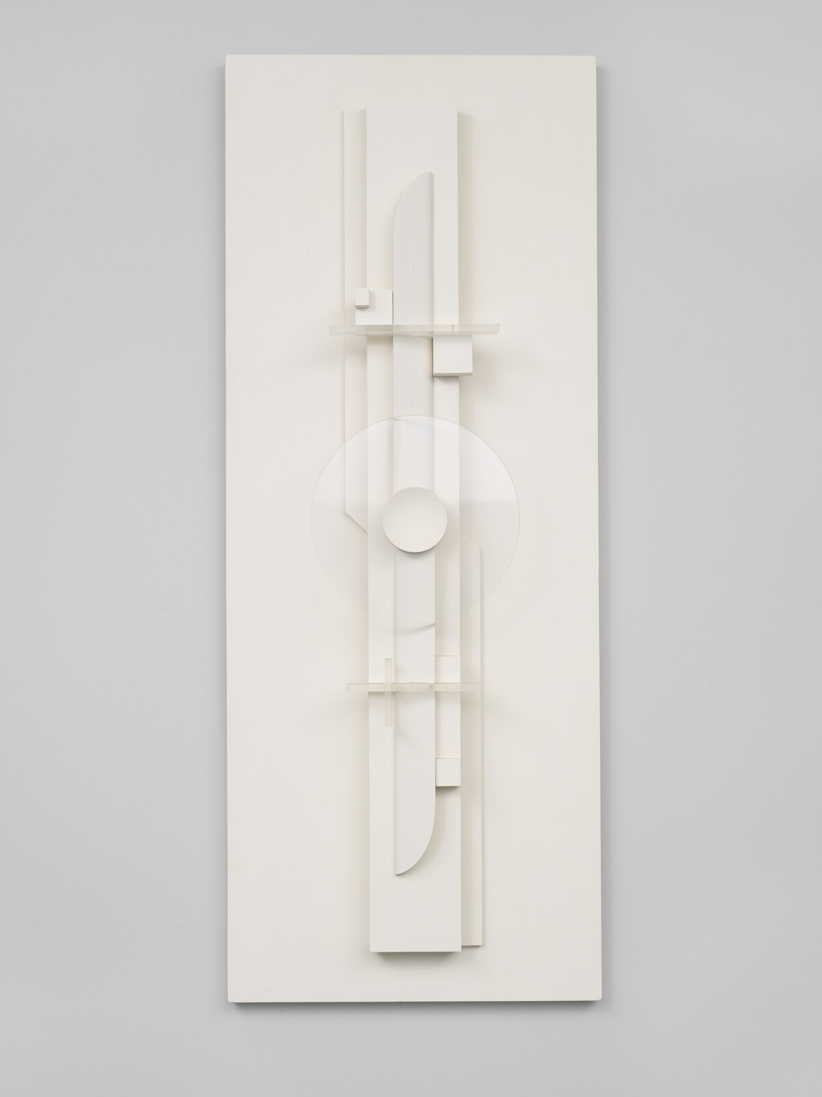 A tall white geometric wall sculpture with stacked rectangles and a central translucent circular disc.