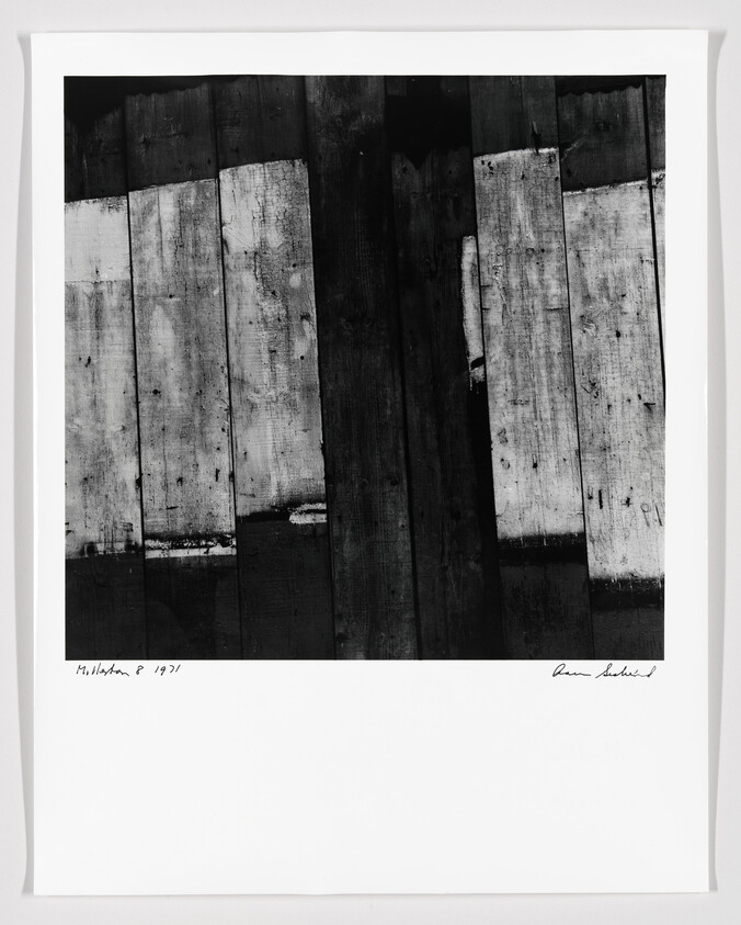 Weathered vertical wooden planks in high-contrast black and white, mounted with a white border.