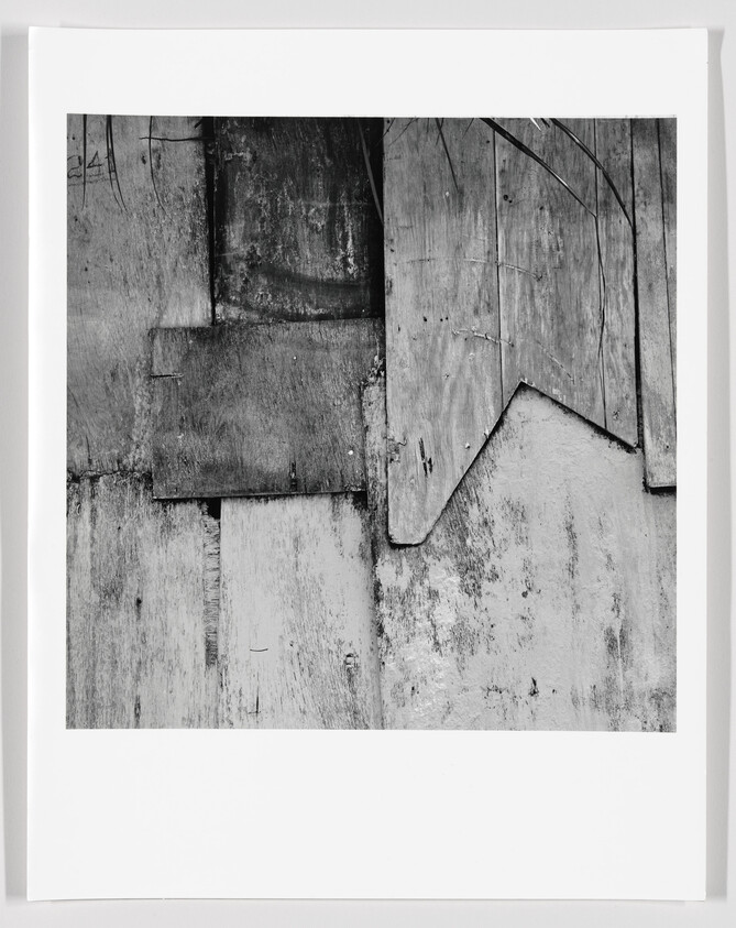 Weathered wooden boards overlapped in irregular shapes showing worn textures and peeling paint.