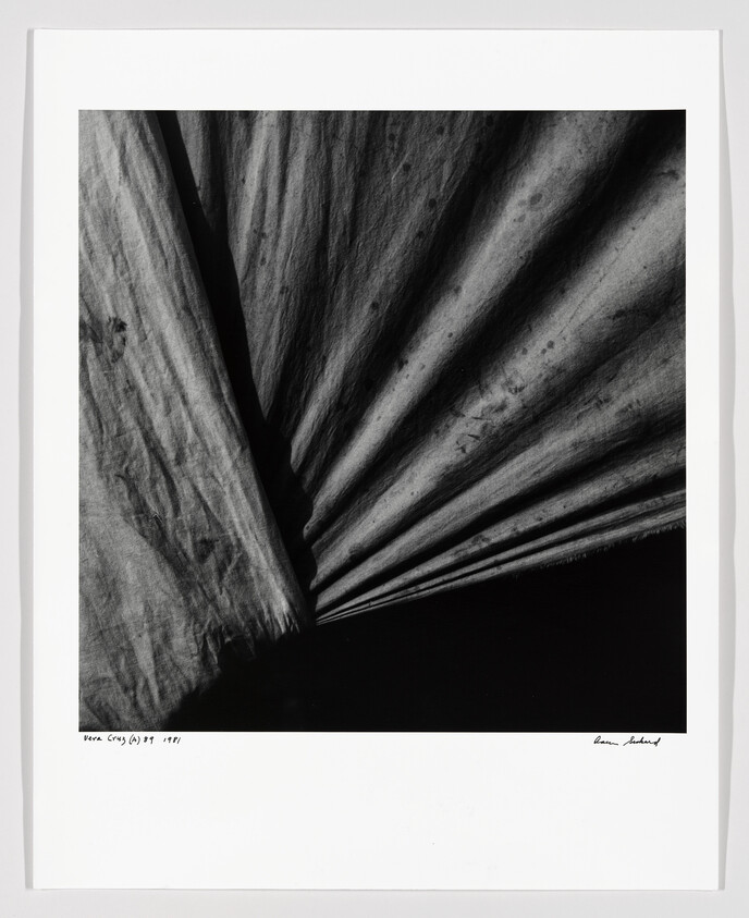 Close-up of dark, pleated fabric fanning out in deep shadows and textured folds.