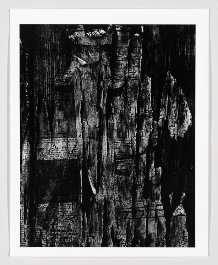 Peeling layered black-and-white posters reveal torn paper textures and faint printed text.