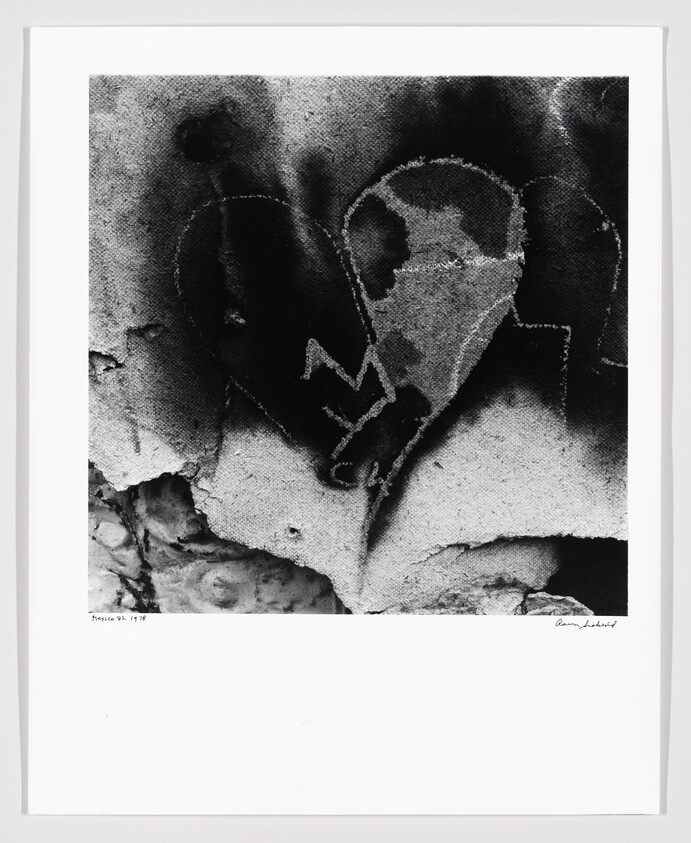 A weathered concrete wall with a spray-painted broken heart and jagged heartbeat line.