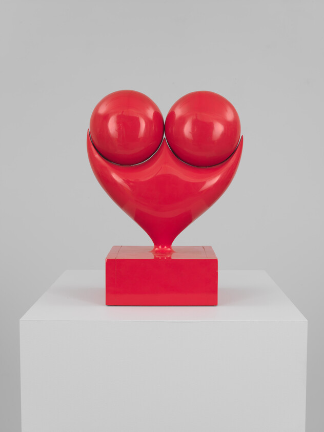 Shiny red abstract heart sculpture with two rounded forms mounted on a pedestal.