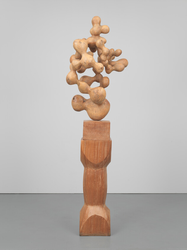 Tall abstract wooden sculpture with bulbous, cloud-like forms mounted on a carved pedestal.