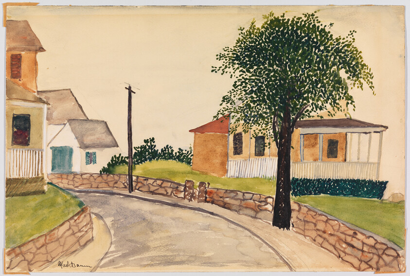 A quiet curved street lined with stone walls, houses, and a large leafy tree.