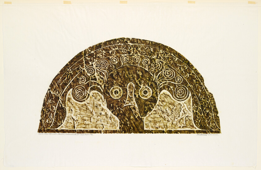 A semicircular carved relief showing a stylized face with spiral patterns and wing-like shapes.