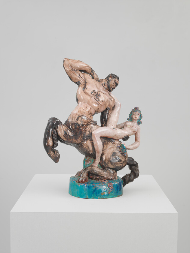 A ceramic centaur struggles while clutching a reclining woman on a turquoise base.