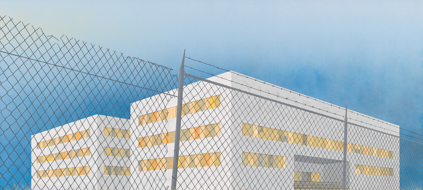 A building with yellow windows behind a chain-link fence against a blue sky.