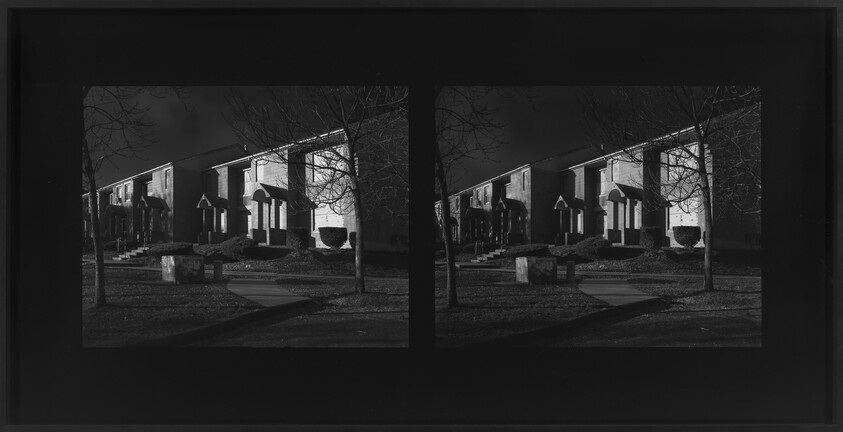 Pair of black-and-white stereoscopic frames showing a row of suburban houses and bare trees at night.