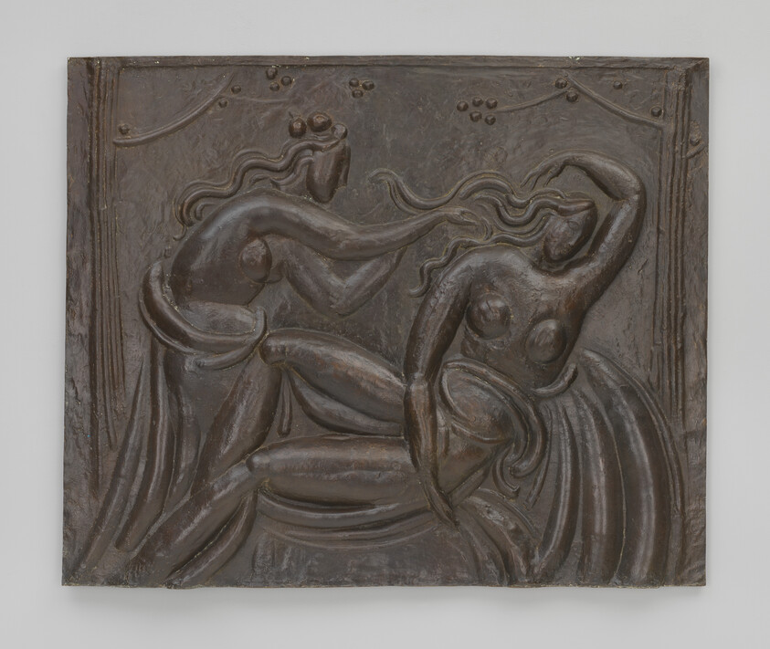 Two nude women with flowing hair in a carved bronze relief, one styling the other's hair.