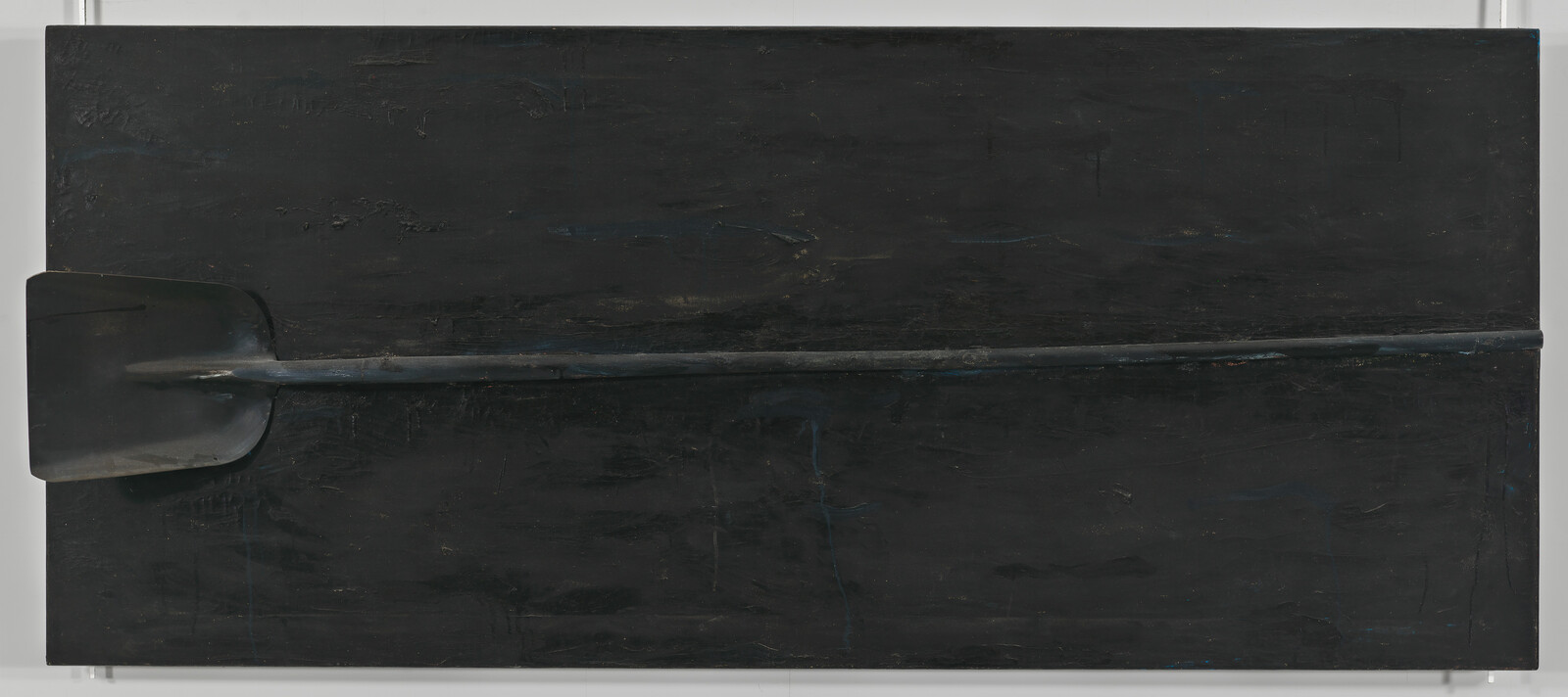 A long dark paddle placed horizontally across a large matte black rectangular panel.