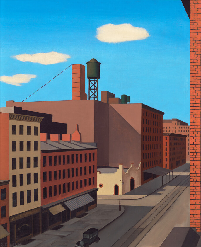 A quiet city block with brick buildings, a rooftop water tower, and a lone parked car.