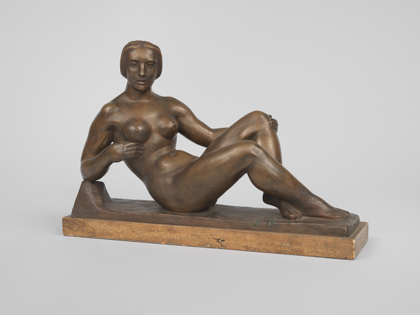 Bronze sculpture of a reclining nude woman resting on a rectangular base.