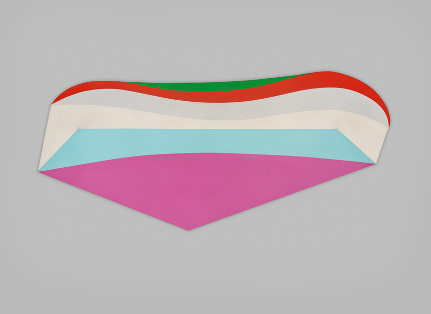 A colorful layered geometric paper sculpture with pink, blue, cream, red, and green bands mounted on a gray wall.