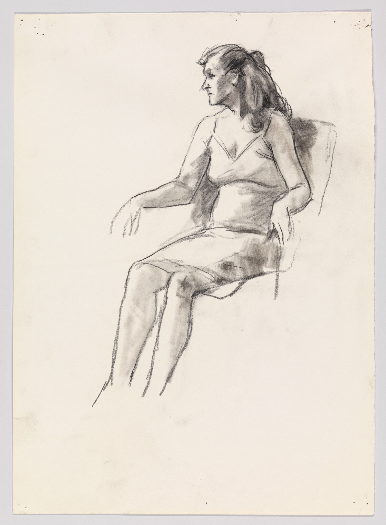 A seated woman in a dress looks to the left with her arms resting on the chair.