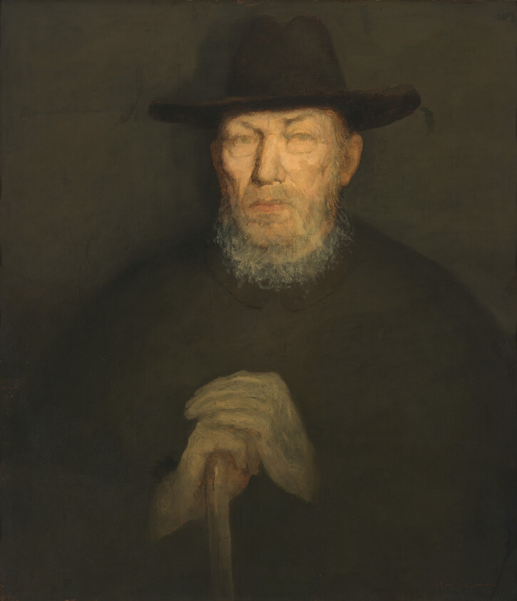 An elderly bearded man in a dark hat resting his hands on a cane.