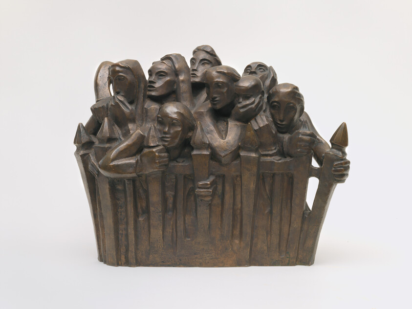 Bronze sculpture of a crowd of figures crowded behind a fence, some holding torches.