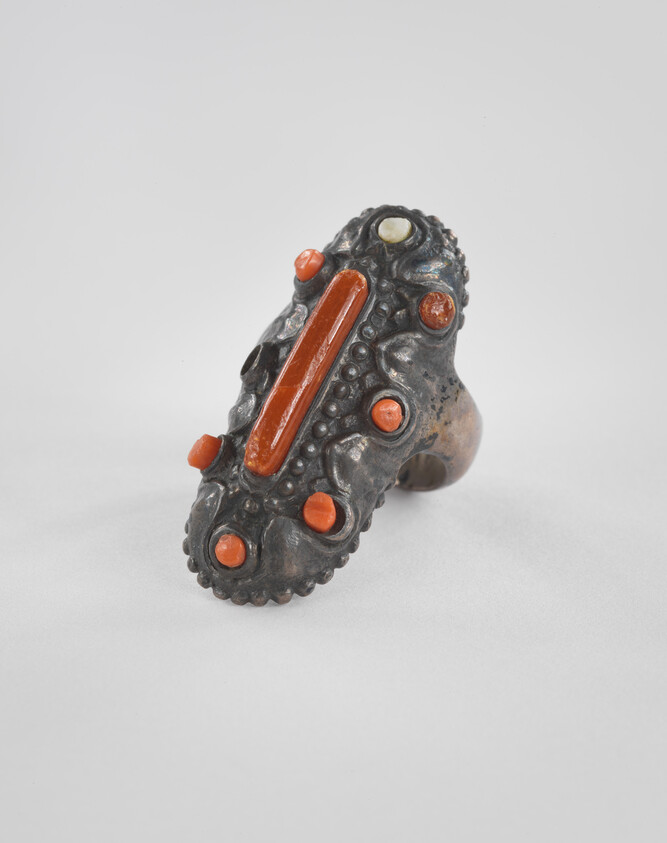 Ornate metal ring with long oval red coral inlay and round coral studs.
