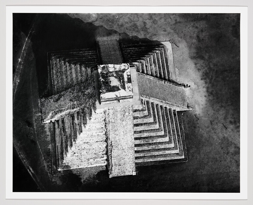 Aerial view shows a large ancient stepped pyramid with four staircases and a central temple platform.