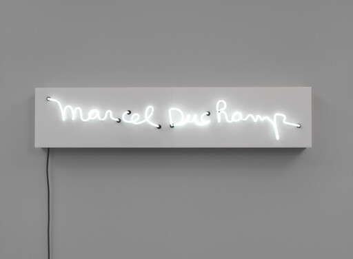 A glowing white neon sign in cursive mounted on a rectangular panel against a gray wall.