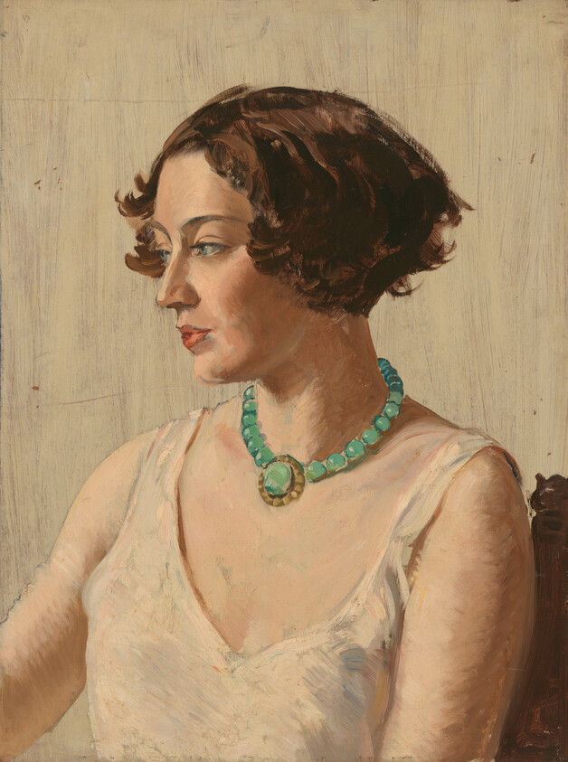 A woman in a sleeveless dress wears a green beaded necklace and looks to the left.