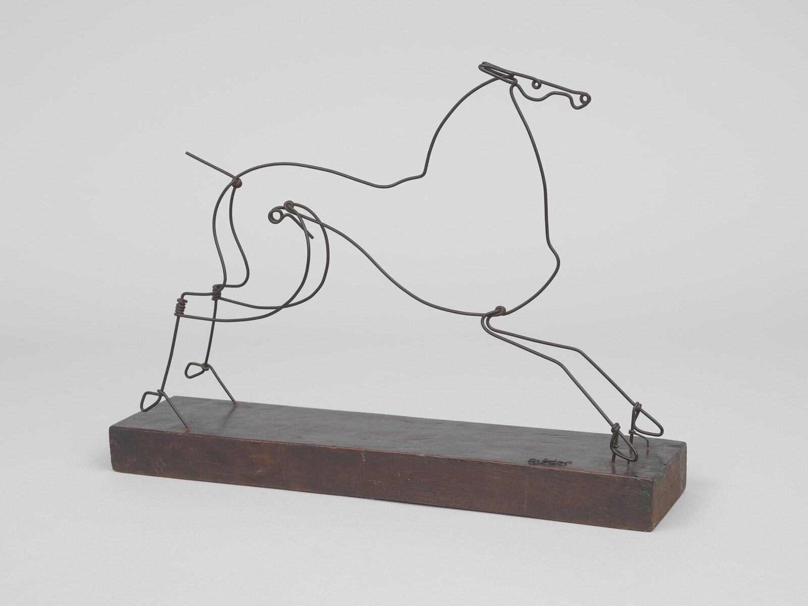 Wire sculpture of a prancing horse formed from continuous metal lines mounted on a wooden base.