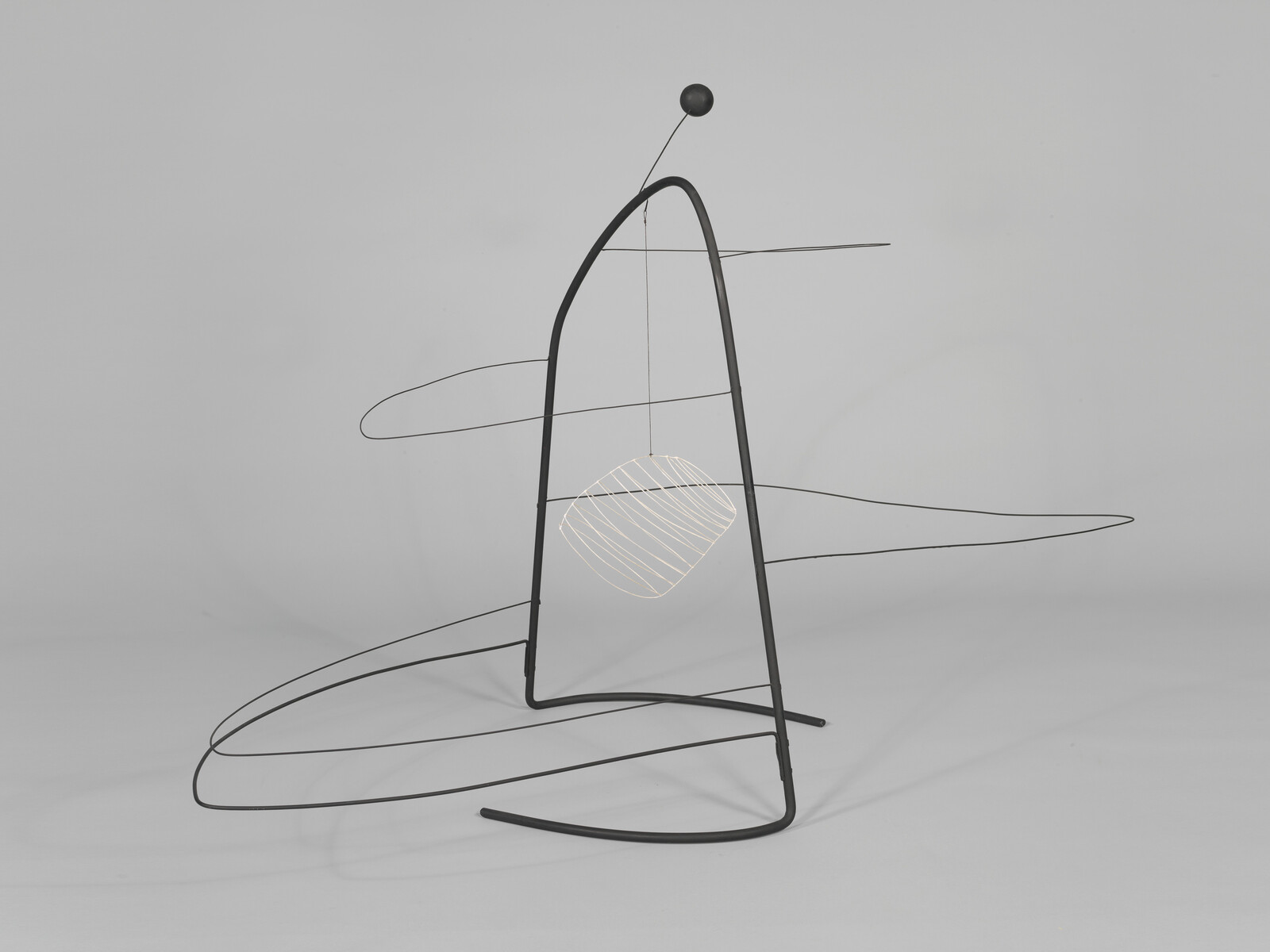 A freestanding metal wire sculpture with curved frame and a suspended striped geometric form.