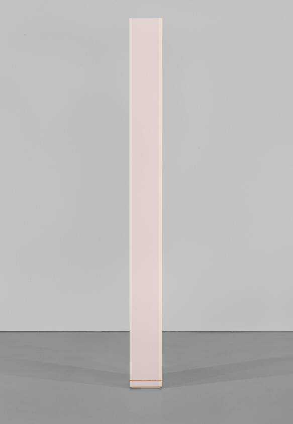 A tall, narrow pale pink rectangular column stands centered on a gray floor against a gray wall.
