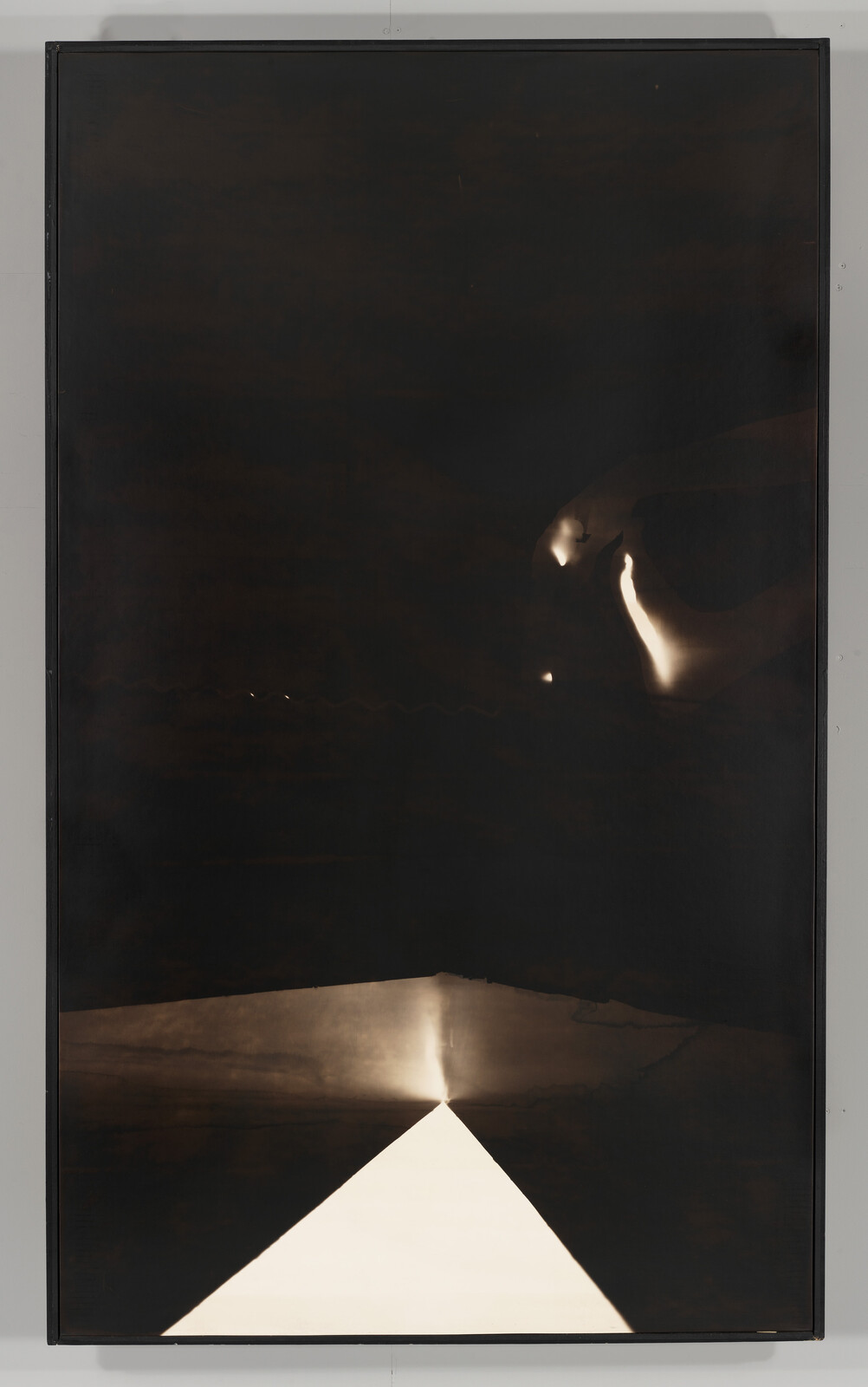 A bright triangular beam of light projects upward from a dark reflective surface.