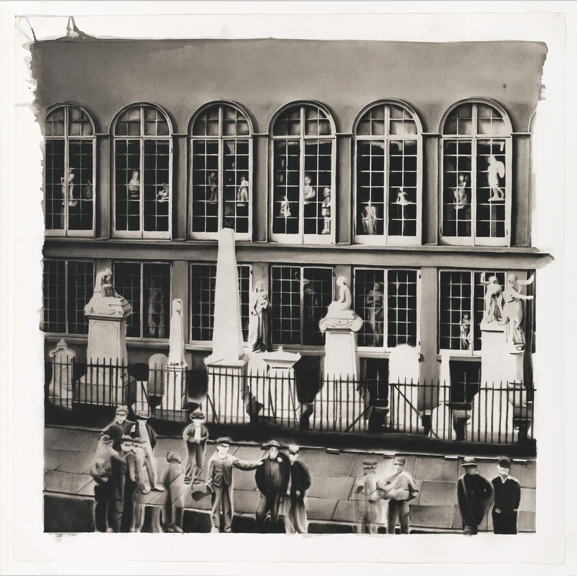 Row of statues behind a fenced building with men standing and talking on the sidewalk.