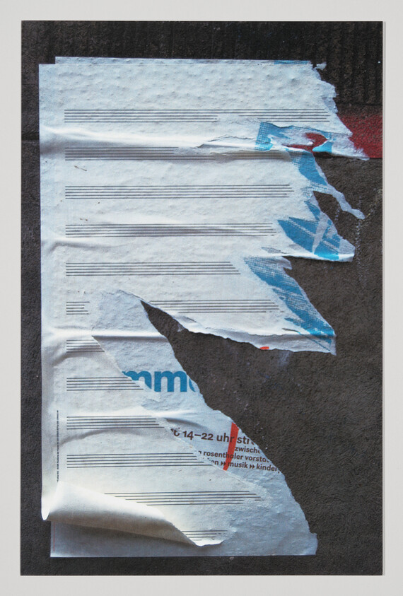 Torn poster with music staff lines peeling away to reveal dark board and blue print.