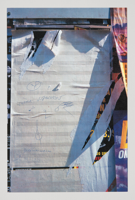 Torn sheet music poster with hand-drawn notes and scribbles peeling from a layered wall.
