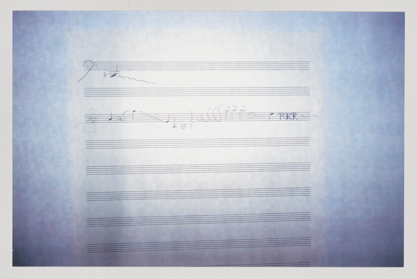 Blank staff paper with a few handwritten musical notes and scribbles near the top.