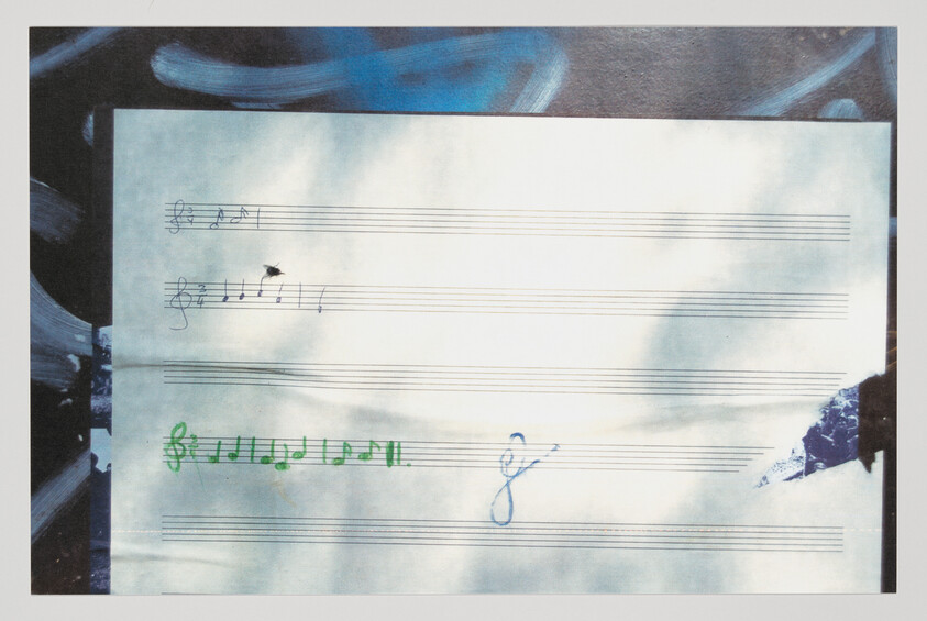 Blank sheet music with three lines of handwritten musical notes and scribbles in black, green, and blue.