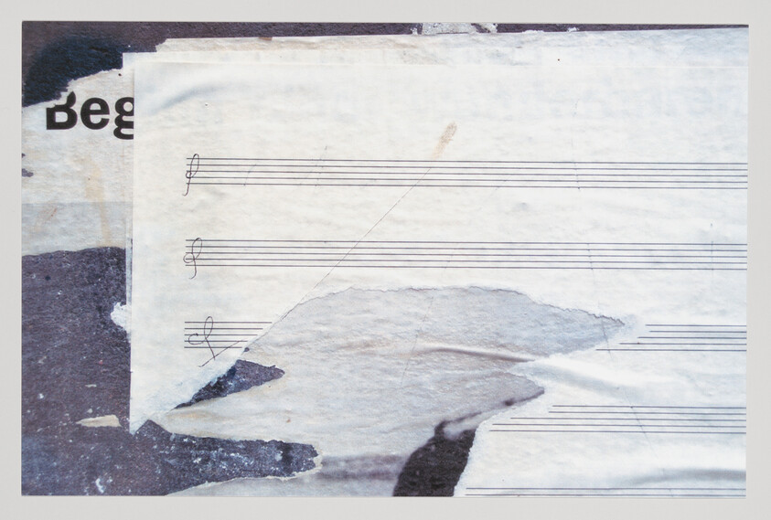 Torn sheet music with blank staff lines and partial treble clefs peeling from a faded wall.