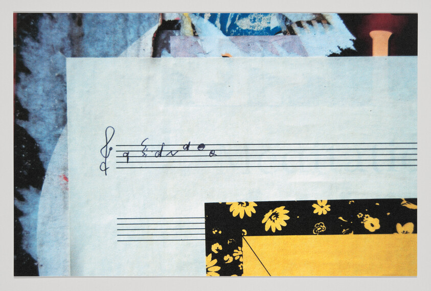 A sheet of music paper with a treble clef and handwritten notes above floral patterned paper.