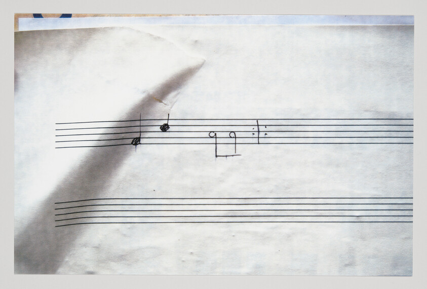A music staff with a few hand-drawn notes and a diagonal crease across the paper.