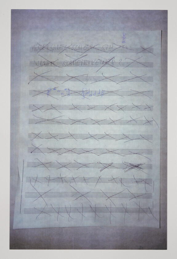 Sheet of staff paper with most measures crossed out and a small section of blue ink notes.