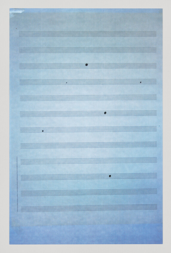Blue music staff paper with scattered black ink dots on several staves.