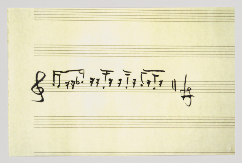 Handwritten musical notation with a treble clef and rhythmic notes on staff paper.