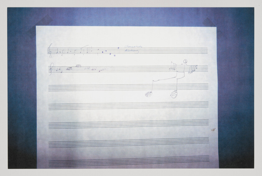 Blank sheet music with a few handwritten notes and a small stick-figure doodle playing guitar.