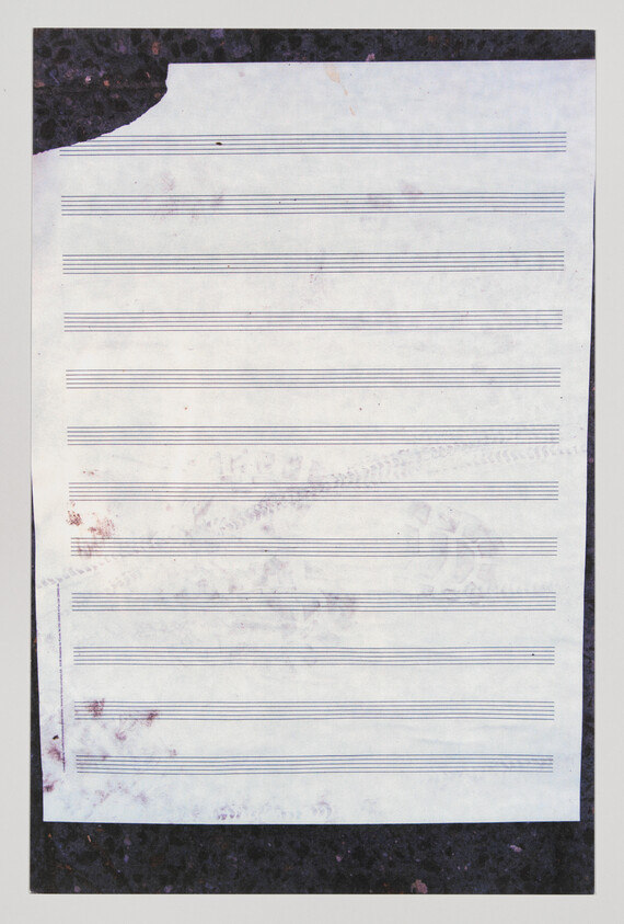 Blank sheet of staff paper with faint smudges and a torn top-left corner.