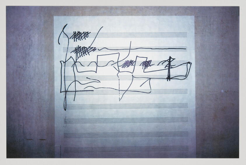 Sheet music with heavy black pen scribbles and crossed-out musical staff lines.