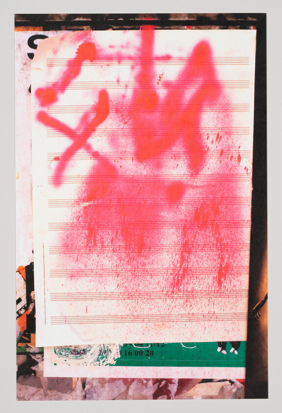 A sheet of music staff paper pasted on a wall is sprayed with bright pink graffiti.