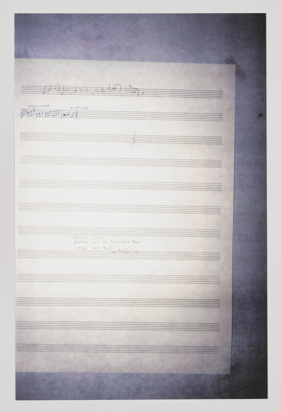 Blank sheet music paper with a few handwritten musical notes and small annotations at the top.