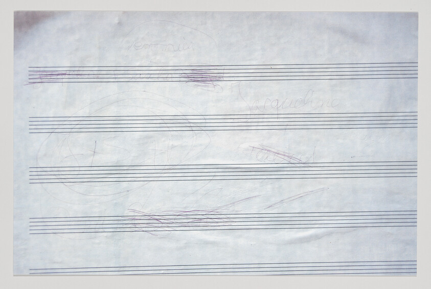 Blank music staff paper with light pencil and pen scribbles and smudges across several staves.