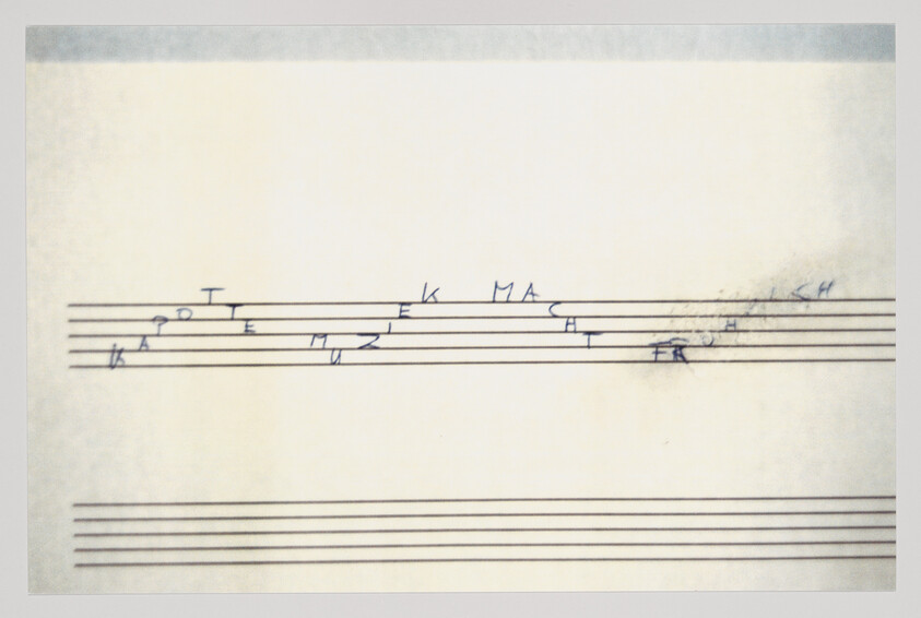 A music staff shows scattered handwritten letters aligned above the top set of staff lines.