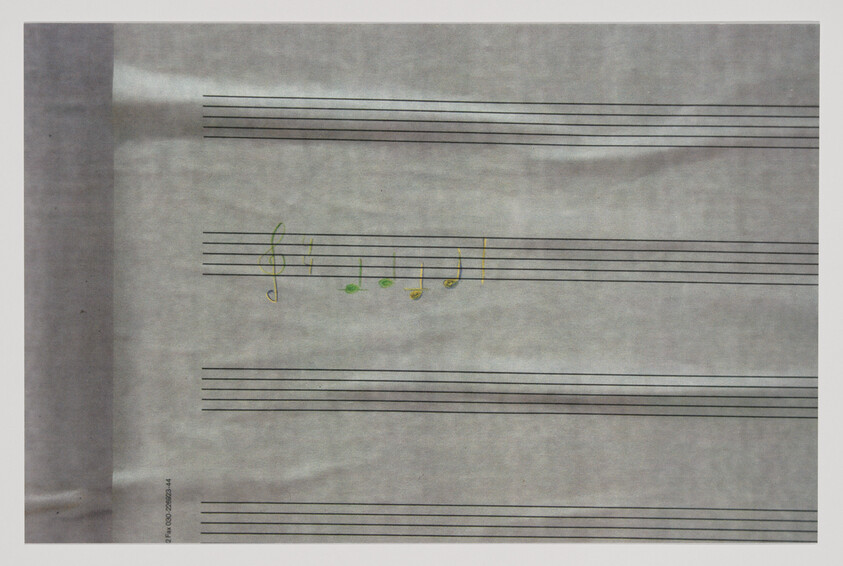 Blank staff paper with a written treble clef and a few green and yellow musical notes.