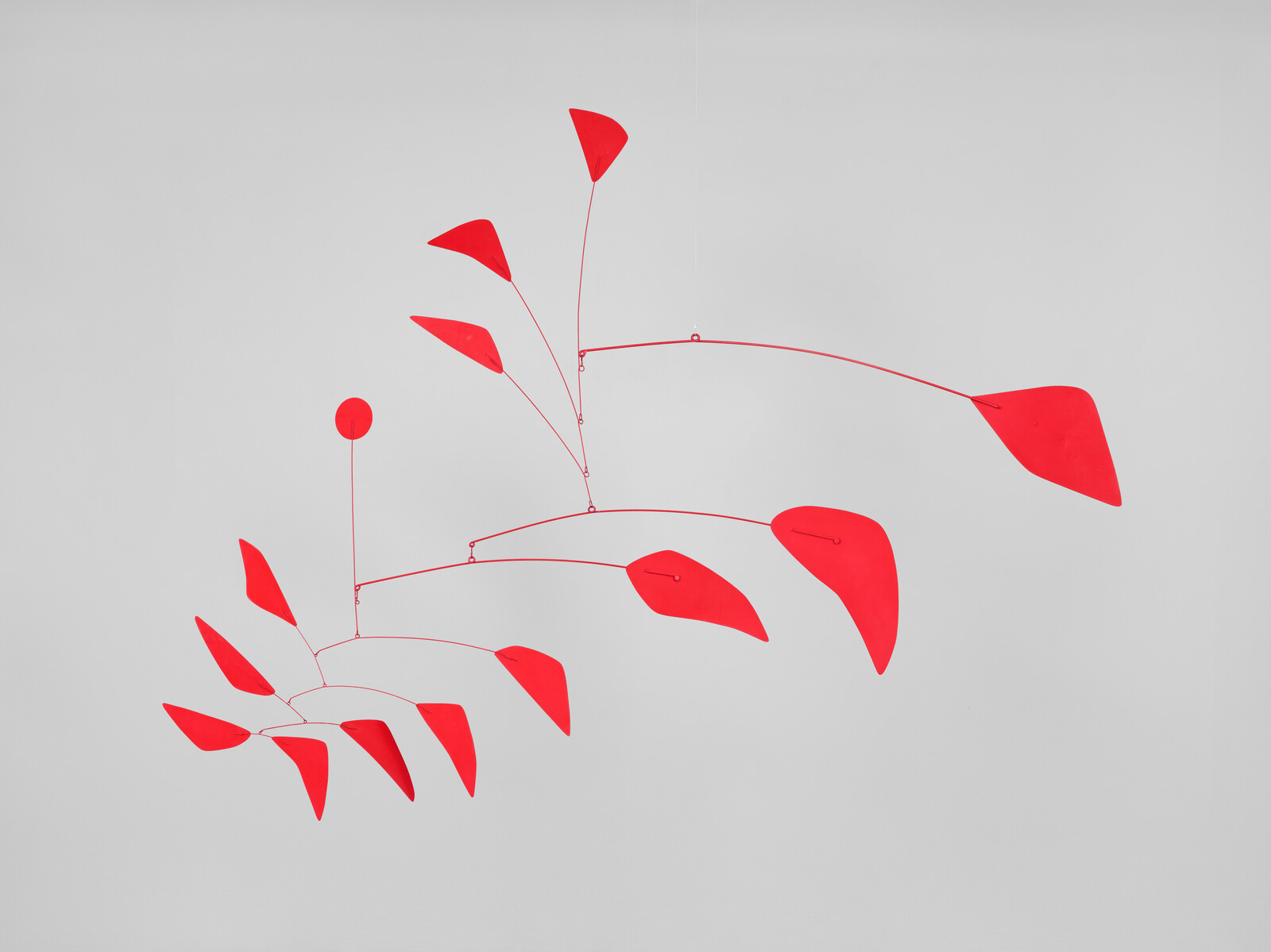 A red hanging mobile with multiple leaf-shaped pieces balanced on thin wires.